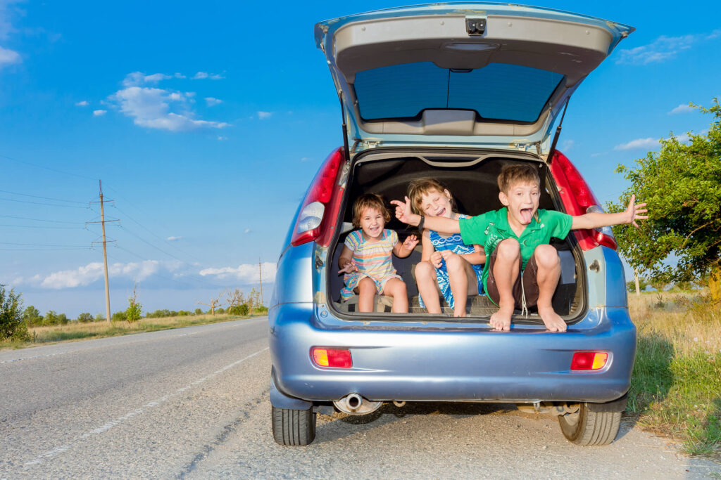 three kids in back of car on a road trip