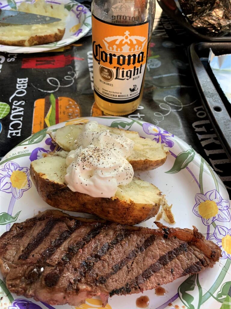 camp cooking steaks baked potato at the campground